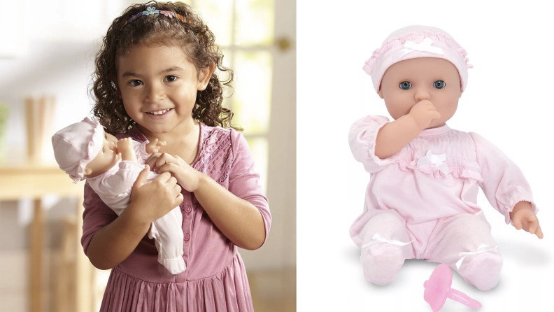 A little girl holds a baby doll