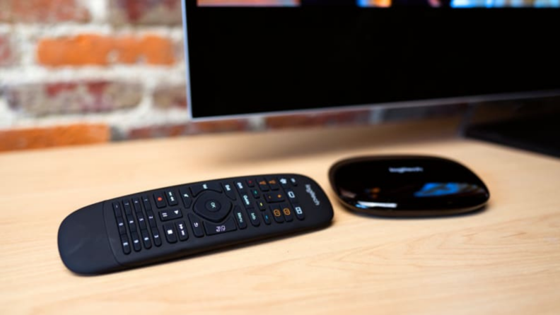 A universal remote and receiver sit on a TV stand in a living room.