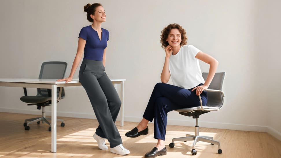 Two women in an office setting smile while modeling comfortable, professional G4free pants.