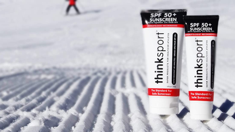 Two tubes of sun screen sit on a snowy hill.