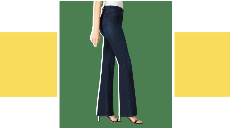 A model wears a pair of dark bell bottom denim jeans.