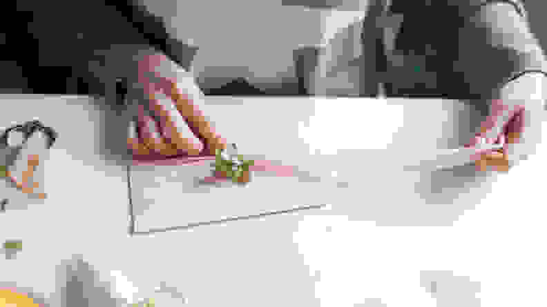 Two hands cutting a velvet ribbon on an envelope, top view