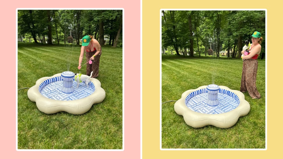 On the right, a woman is filling up the Minnidip Luxe Inflatable Fountain Sprinkler with a water hose, outside. On the left, a woman is holding a dog, standing next to theMinnidip Luxe Inflatable Fountain Sprinkler outside.