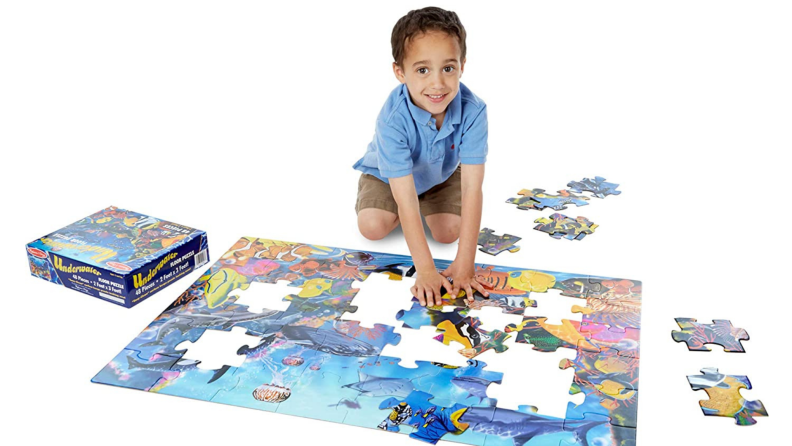 A child puts together a large floor puzzle.