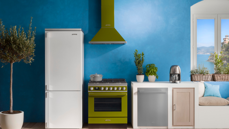 A green oven and range hood from Smeg sits in a blue kitchen.