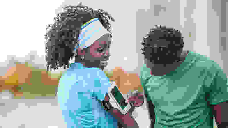 一个女人向跑步的伴侣展示了手机绑在手臂上。