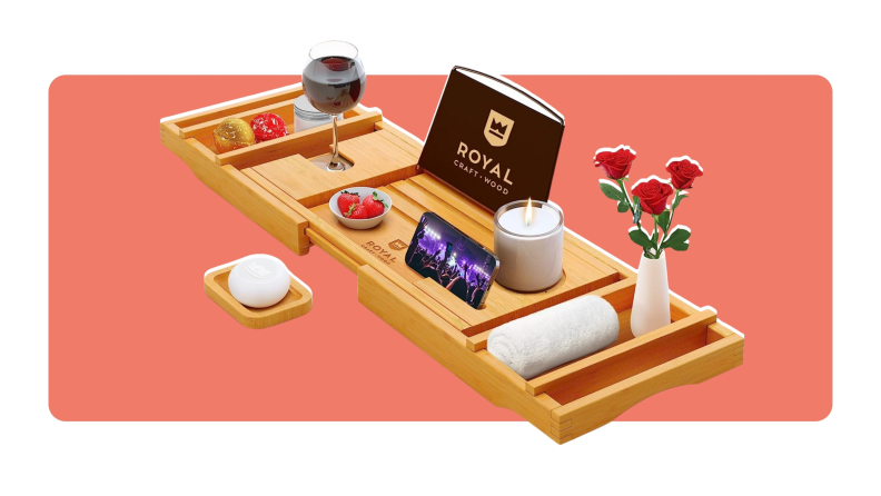 A wooden bath tray with assorted self-care items, a candle, a vase of red roses and a glass of wine.