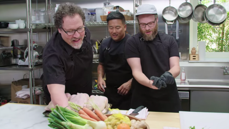 A still from The Chef Show featuring Roy Choi, Jon Favreau, and Seth Rogen cooking in an industrial kitchen.