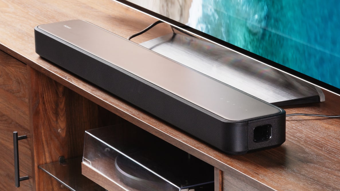 The Sony HT-S2000 soundbar sitting on a wood entertainment center, next to a TV.