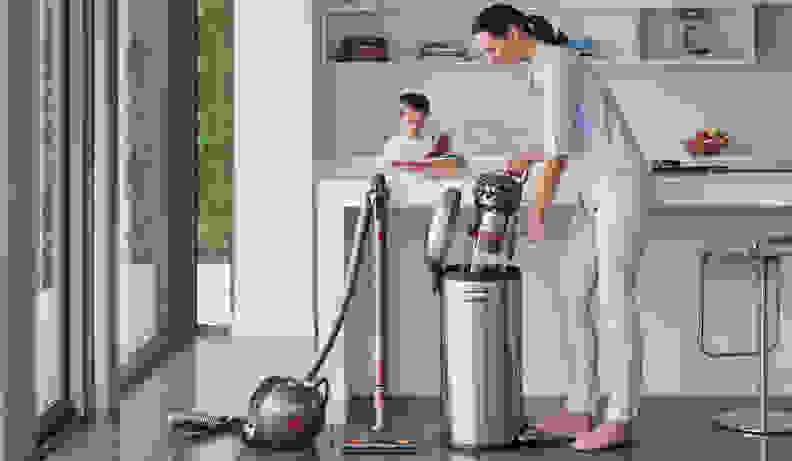 A woman emptying a Dyson vacuum into the trash