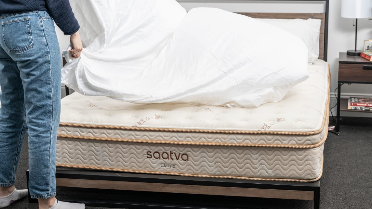 Person putting sheets on Saatva Classic mattress