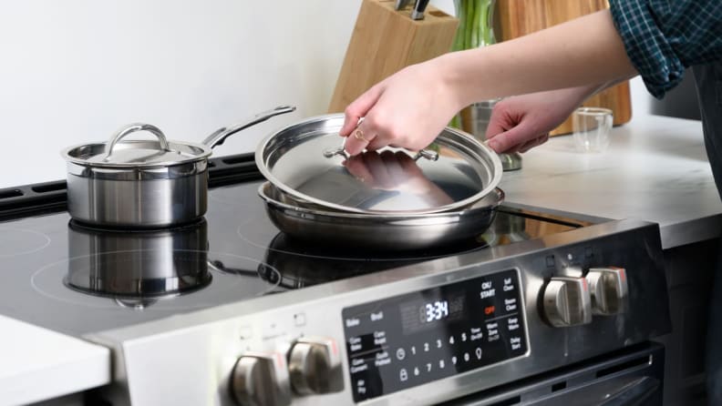 Woman covering pan with lid as she cooks