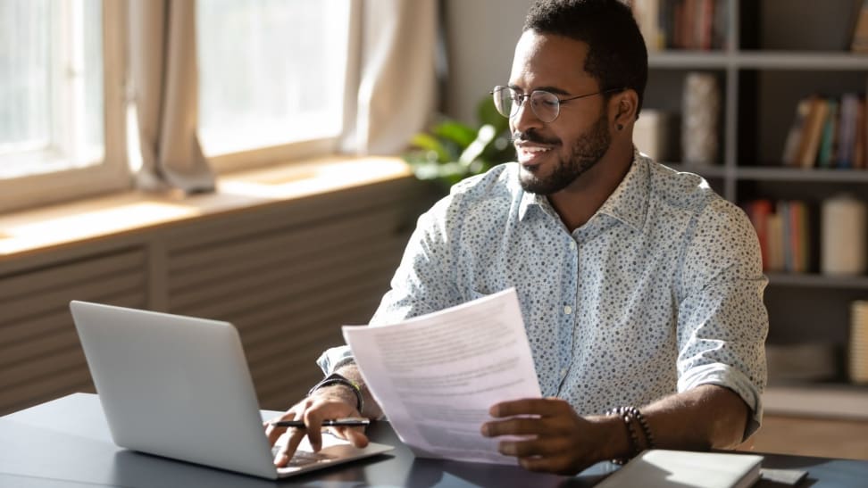 Man sitting at desk in home office with laptop and paperwork