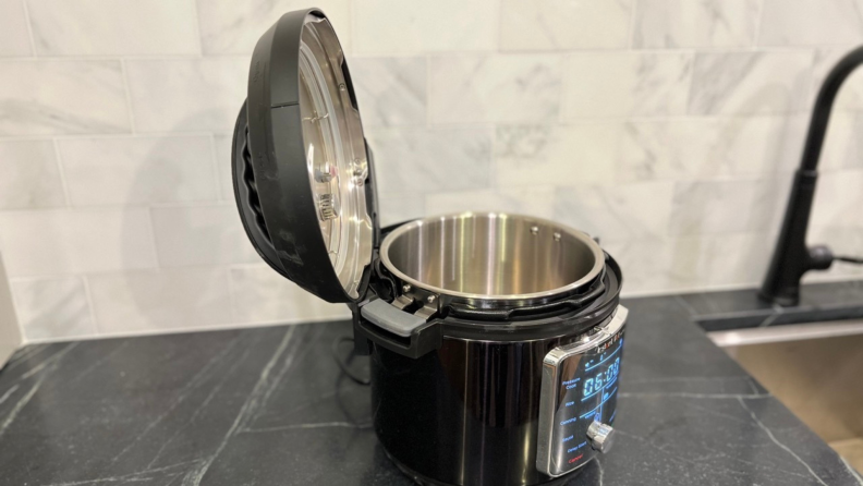 An Instant Pot Pro sitting on a counter with the lid open and connected to the special hinge.