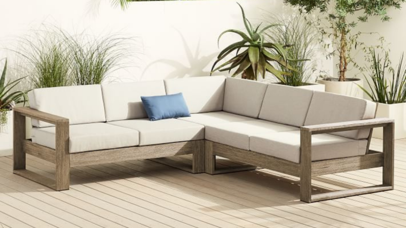 An l-shaped outdoor sofa with white cushions.