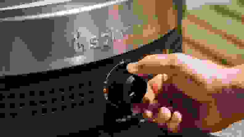 Hand adjusts temperature settings with knob on the Solo Pi Prime oven.