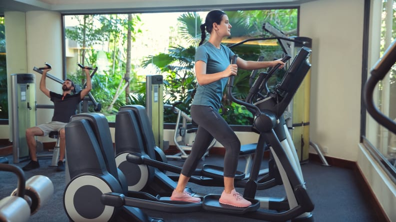 A woman using an elliptical machine at the gym.