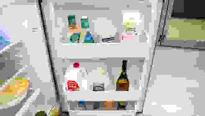 Silver refridgerator with door open showing food on shelves