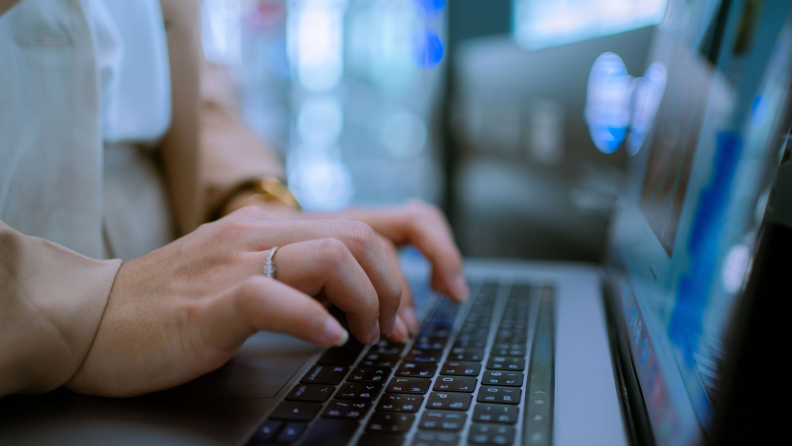 Person typing on laptop computer at table.