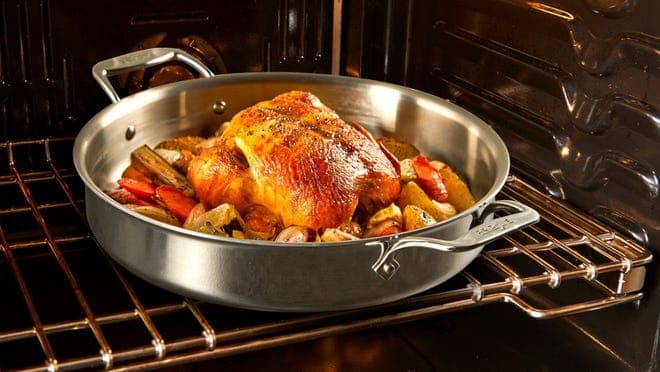 A chicken and vegetables bake inside an oven.