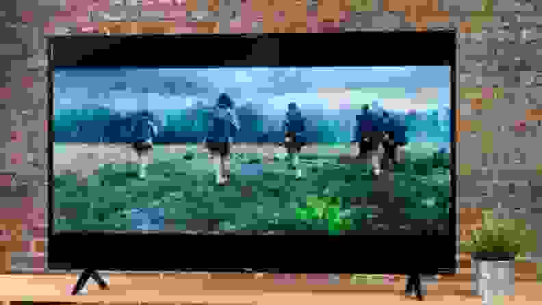 A TV showing a drama against a brick wall.