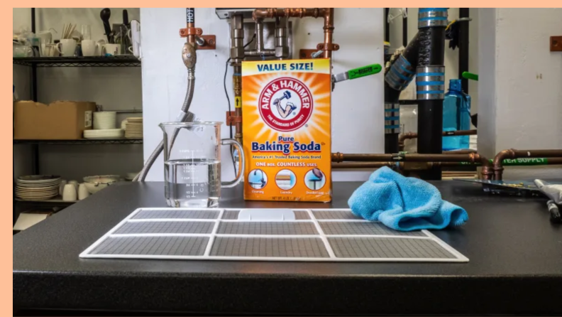 A box of baking soda sits near the removed A/C filter.