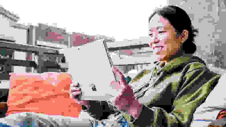 A woman sitting outside, holding the Pro 8 in tablet mode.