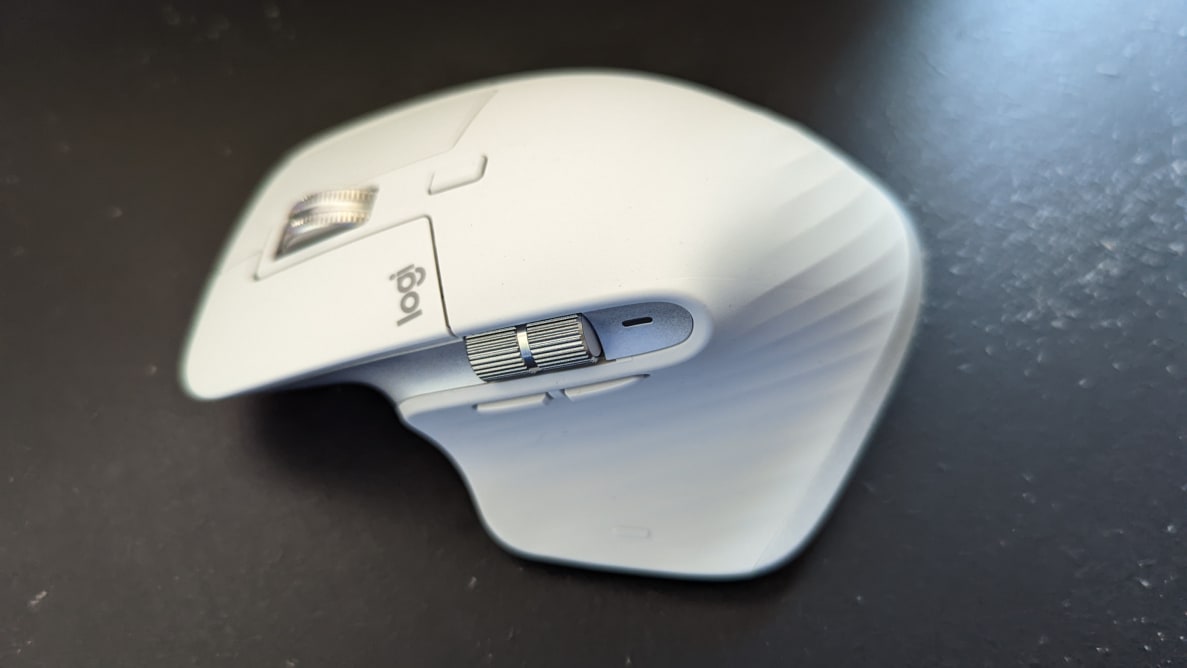A white Logitech computer mouse sits on a surface.