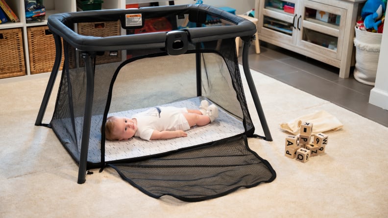 A baby laying in a playard with the side unzipped
