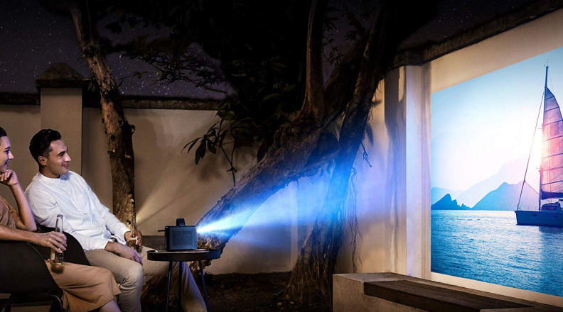 Two friends sitting outdoors enjoying a film being displayed by the Nebula, by Anker, Mars II