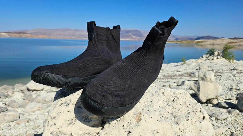 Black Vessi shoes drying out atop some rocks under the sun.