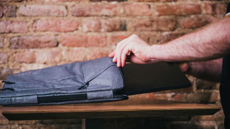The MSI Prestige being put into the included laptop sleeve accessory.