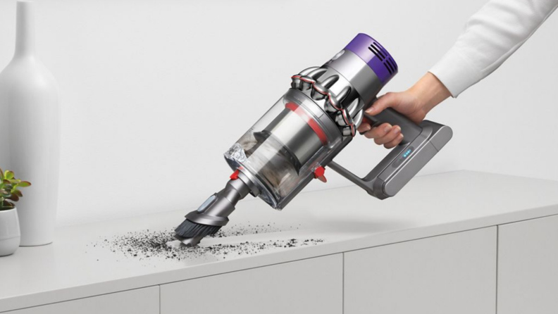 A person vacuums a mess with a Dyson vacuum.