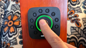 A person's finger pressing buttons on a smart door lock