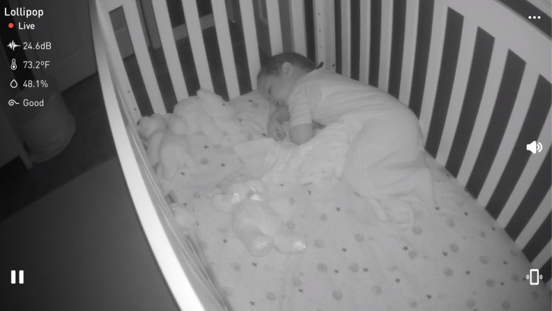 Black and white video footage of small child sleeping inside of baby crib with date and time on screen.