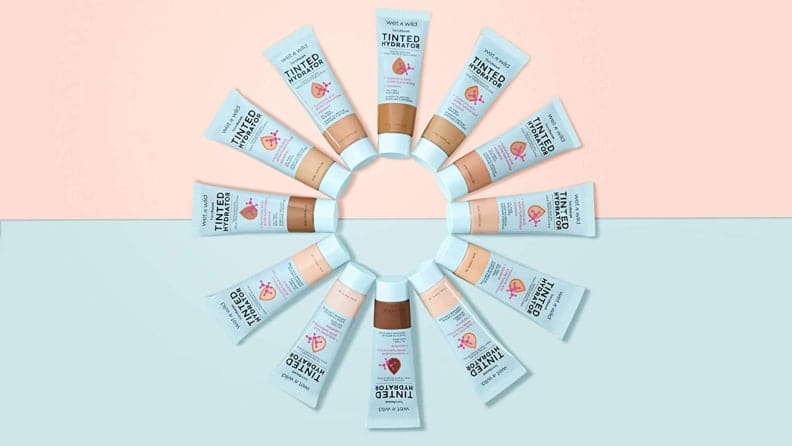 All of the shades of the Wet n Wild Bare Focus Tinted Hydrator are in a circle with a pink and blue background behind them.