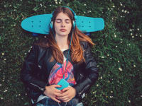 girl listening to music while laying down on her skateboard