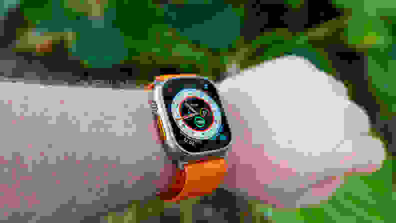 The Apple Watch Ultra on a man's wrist, against the backdrop of a tropical jungle