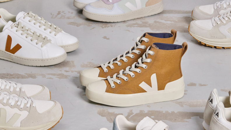 Multiple pairs of Veja sneakers on a gray surface.