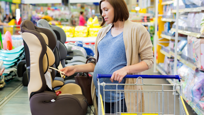 Pregnant woman in shop buying a baby car seat.