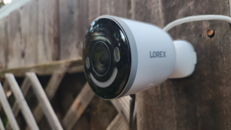 Lorex 4K Spotlight mounted on wooden fence outdoors.