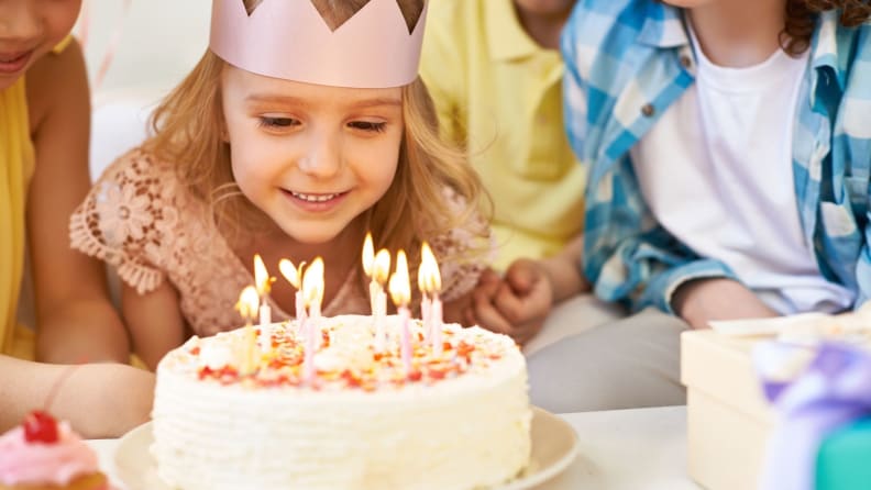 Happy little girl wearing a birthday crown getting ready to blow out her birthday candles