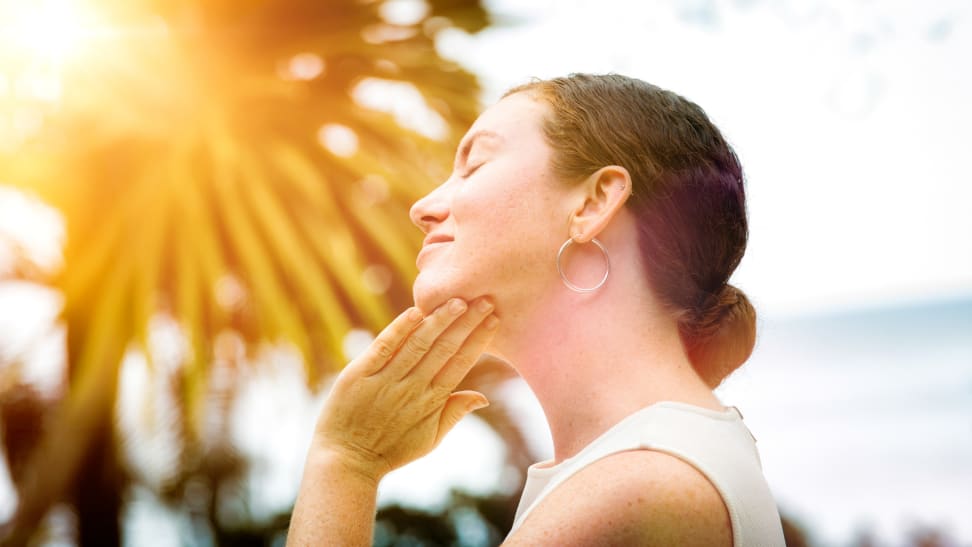 A woman standing in the sun with her hand placed under her chin