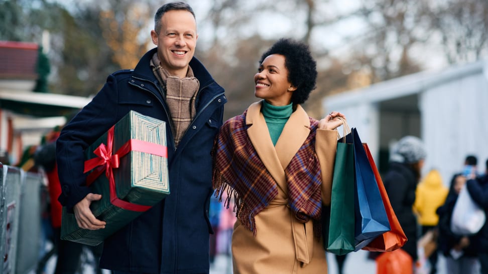 Happy couple shopping outdoors while holding bags in their hands.