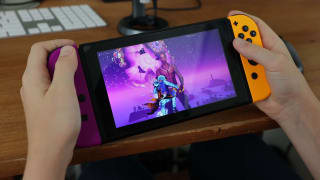 Person holds a Nintendo Switch while playing Fortnite