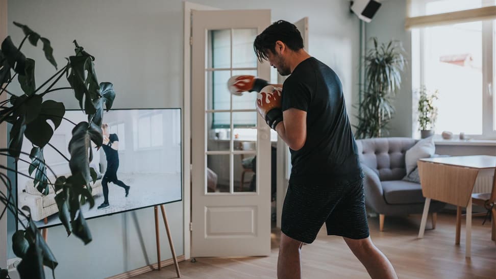 A man shadow boxing in front of his TV.