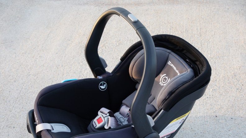 The Uppa Baby Mesa V2 car seat sitting on the pavement with the handle raised.