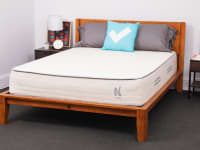 The Nolah Natural mattress inside of a wooden bed frame in bedroom.