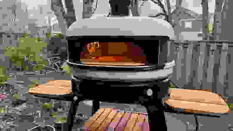Gozney pizza oven in an outdoor setting with a flame visible inside