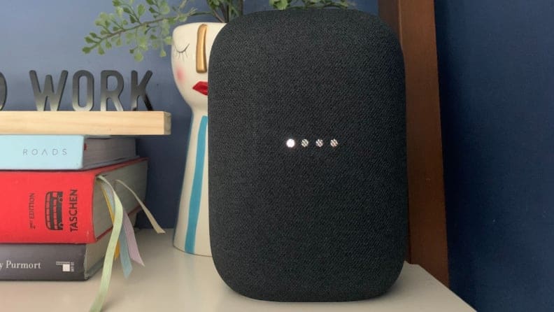 Google's Nest Audio smart speaker sits on a bookshelf.